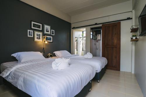 two beds in a bedroom with white sheets and towels at Cozy Inn Chiang Mai in Chiang Mai