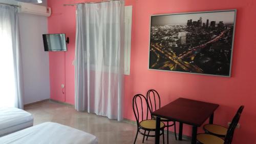 イラクリトサにあるToula Apartmentsの赤い壁の客室で、テーブルと椅子が備わります。