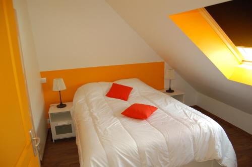 ein Schlafzimmer mit einem Bett mit zwei roten Kissen darauf in der Unterkunft Gites la charretterie in Ourville-en-Caux