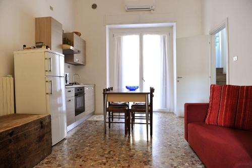 eine Küche mit einem Tisch, einem Kühlschrank und einer roten Couch in der Unterkunft Casa San Paolo in Sarnico