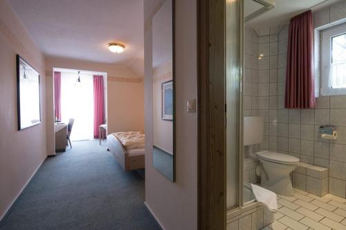 a bathroom with a toilet and a bed in a room at Kleines Hotel Wemhoff in Winterberg