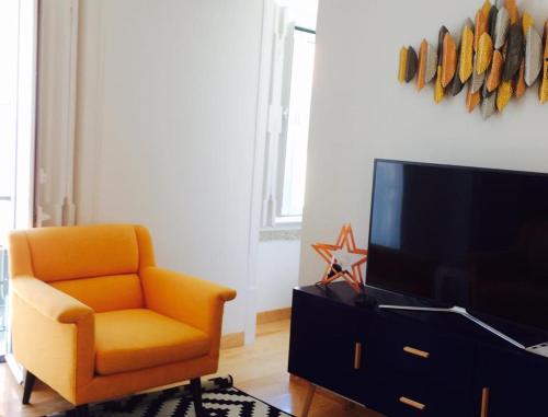 a living room with an orange chair and a television at Apartments Alfacinha Ajuda in Lisbon