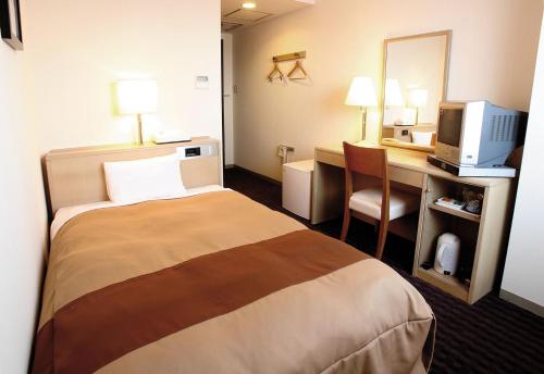 a hotel room with a bed and a desk with a computer at Hirosaki Plaza Hotel in Hirosaki