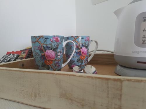 two coffee mugs in a wooden drawer next to a toaster at Foresteria Villa Margherita in Colico