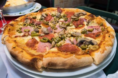 a pizza sitting on top of a white plate on a table at Hotel Benidorm Panama in Panama City