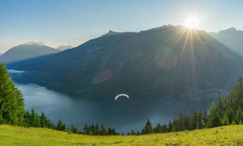 a paraglider flying over a lake in the mountains at Alpenvital Tirol Appartements in Pertisau