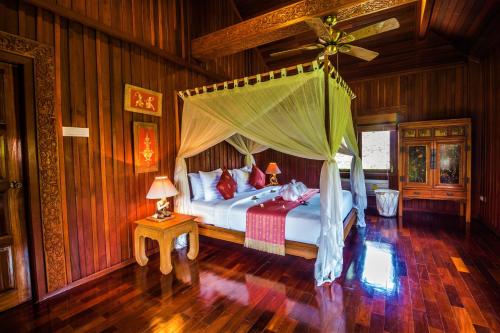 a bedroom with a bed with a canopy at Erawan Villa Hotel in Bangrak Beach