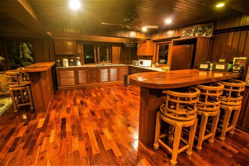 a kitchen with wooden floors and a bar with stools at Erawan Villa Hotel in Bangrak Beach