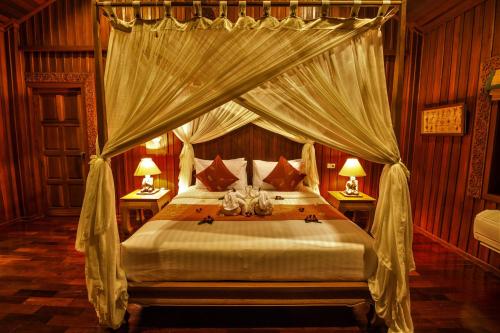 a bedroom with a canopy bed with two lamps at Erawan Villa Hotel in Bangrak Beach