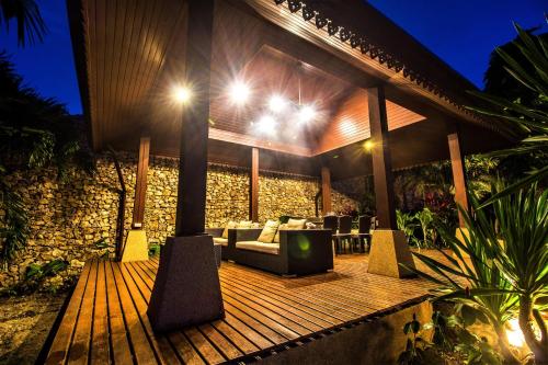 a wooden deck with a couch and chairs on it at Erawan Villa Hotel in Bangrak Beach