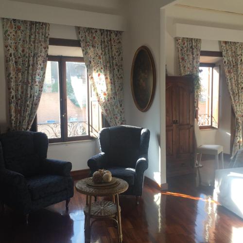 a living room with two chairs and a table and windows at Catherine's Home in Rome