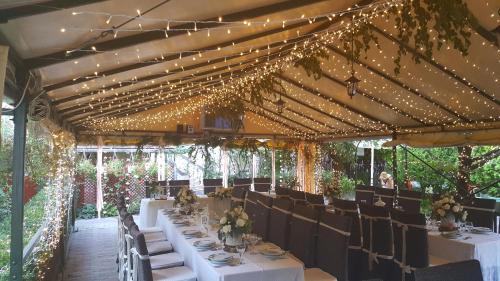 a dining room with white tables and chairs and lights at Illés Hotel in Szeged