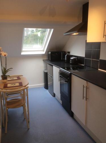 a kitchen with black counters and a table and a window at Olde Lantern Holiday Lets in Ilfracombe