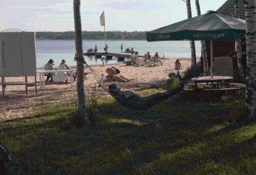 a person laying in a hammock on a beach at Atpūtas komplekss Lilaste in Lilaste