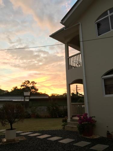 a house with the sunset in the background at Flower Garden Self-Catering Apartments in Beau Vallon