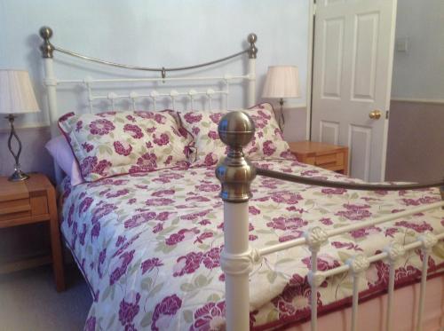 a bedroom with a bed with a floral comforter at StoneLaw Cottage in Longframlington