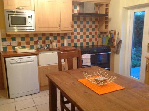 a kitchen with a wooden table and a microwave at StoneLaw Cottage in Longframlington