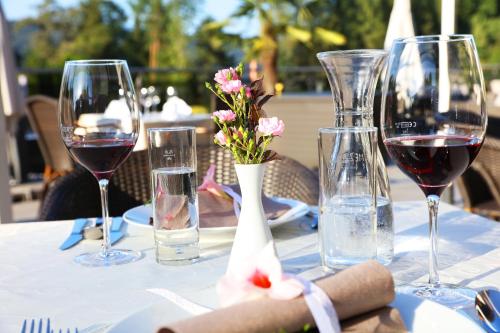 a table with glasses of wine and flowers on it at Dei Hotel Schönblick in Velden am Wörthersee