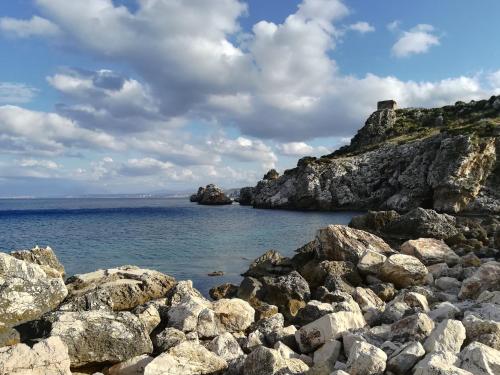 a rocky shore with a castle on top of it at Piccola Baia in Scopello