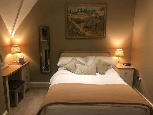 a bedroom with a large bed with two tables and two lamps at The Six Bells in Bourne