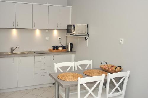 a kitchen with a table and chairs and a microwave at Apartament Martini in Kołobrzeg