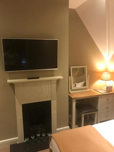 a room with a fireplace with a flat screen tv on top at The Six Bells in Bourne