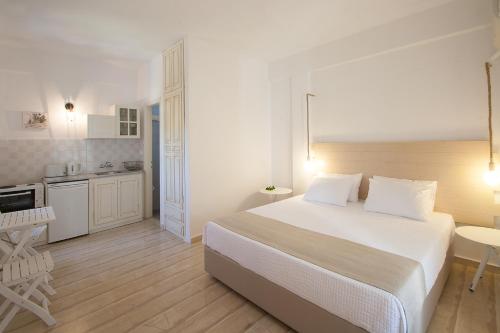 a white bedroom with a bed and a kitchen at Paris Studios & Apartment in Agia Paraskevi