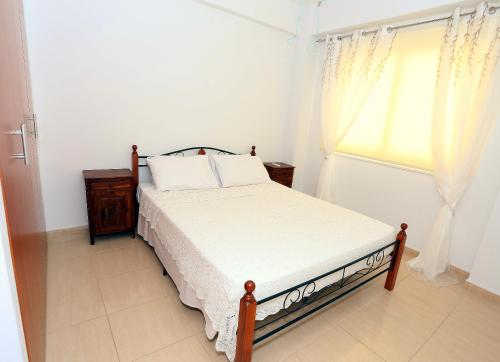 ein weißes Schlafzimmer mit einem Bett und einem Fenster in der Unterkunft Penelope Court Apartment 102 in Larnaka