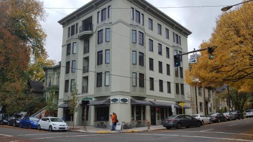 un edificio blanco en una calle de la ciudad con coches aparcados en Northwest Portland Hostel en Portland