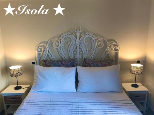 a bed with a white headboard and two lamps at La Terra dei Mari Room & Relax in Pachino