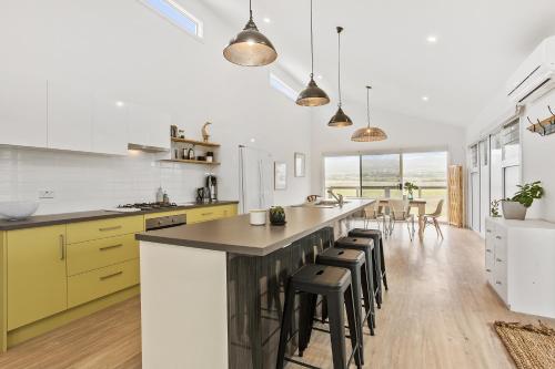 a kitchen with yellow cabinets and a large island with bar stools at Sea View at Silver Sands - C21 SouthCoast Holidays in Aldinga Beach