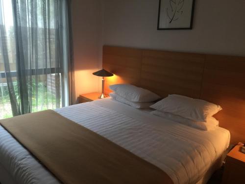 1 dormitorio con 1 cama blanca grande y ventana en Beachside Apartments Bonbeach en Bonbeach