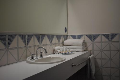 a bathroom with a sink and a mirror and towels at Admiral Motel Bunbury in Bunbury