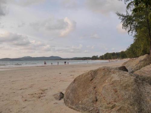 a group of people on a beach with a large rock at Chill land house in Bang Tao Beach