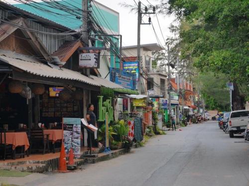 a city street with shops on the side of the road at Chill land house in Bang Tao Beach