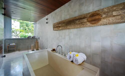 a bathroom with a tub and a sink with towels at Planta Boutique Resort in Canggu