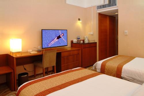 a hotel room with a desk with a computer and a television at Guangdong Hotel in Guangzhou
