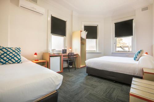 a hotel room with two beds and a desk at Melton Hotel Auburn in Sydney