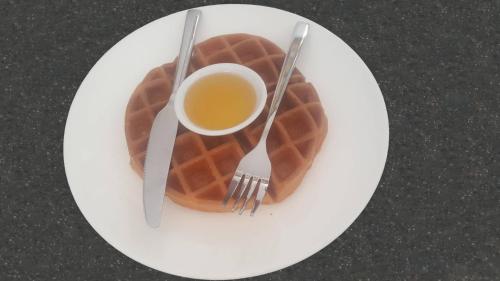 a plate with a cup of coffee and a waffle at Bou Savy Villa in Siem Reap