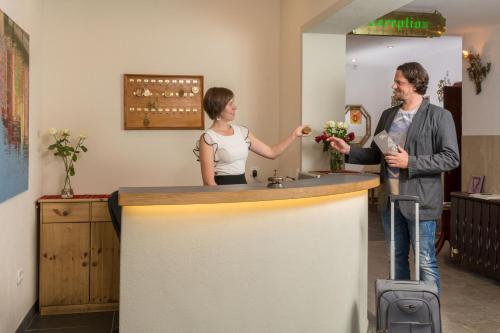 een man en een vrouw die aan een balie staan bij Hotel Gisela in Kufstein