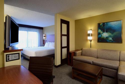 a hotel room with a bed and a couch at Hyatt Place Dallas Las Colinas in Irving