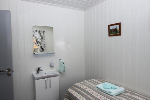 a white bedroom with a bed and a sink at Guesthouse Steindórsstadir, West Iceland in Reykholt