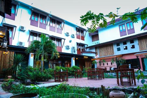 a courtyard with tables and chairs in a building at Charming Lao Hotel in Ban Chéng