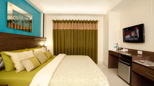 a bedroom with a large bed and a television at BIZZ Tamanna Hotel in Pune