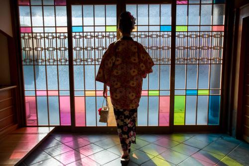 een vrouw kijkt naar een kleurrijke glazen deur bij Kinosaki Onsen Hanakouji Saigetsu in Toyooka