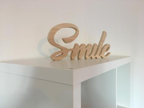 a wooden sign that reads smile sitting on a white table at Sleep in Paris Val d'Europe in Chessy