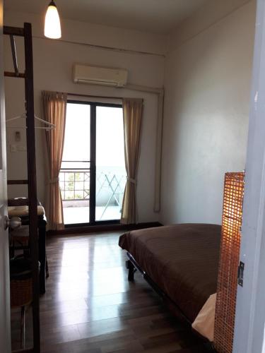 a bedroom with a bed and a large window at Lamphuhouse Bangkok in Bangkok