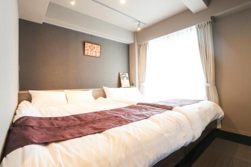 a bedroom with a large bed with a window at Apartment Hotel 7key S Kyoto in Kyoto