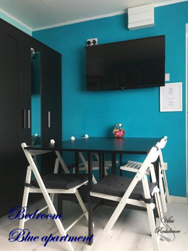uma mesa de jantar com duas cadeiras e uma televisão numa parede azul em Vika Residence Deluxe Apartments Wednesbury Holiday Resort em Wednesbury