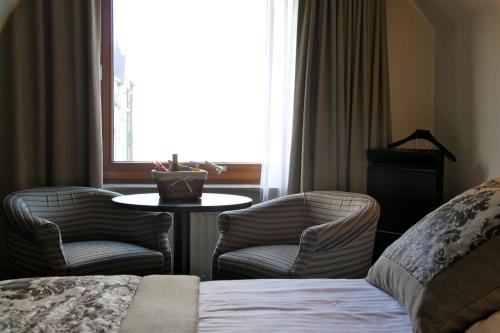 a hotel room with a bed and chairs and a window at Hotel Iris in De Panne